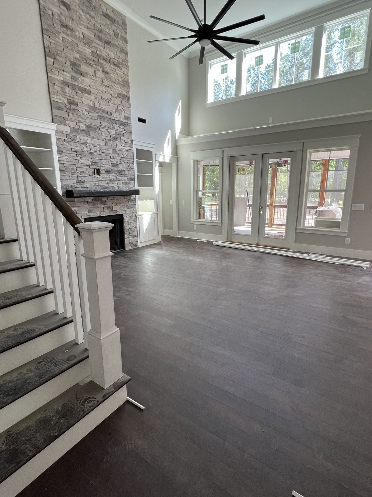 Dark wide-plank floor in a two-story great room with a stone fireplace