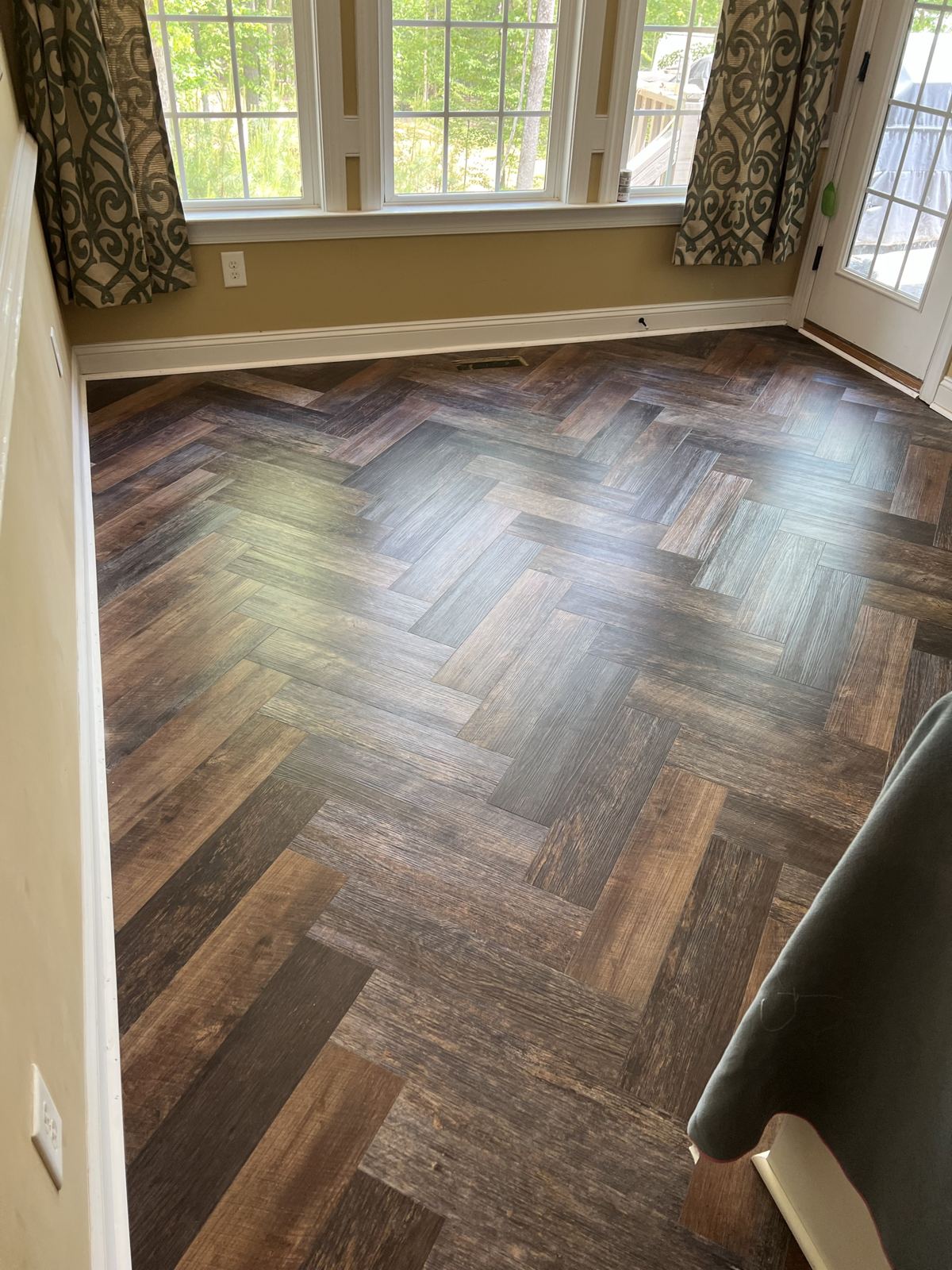 Dark multi-tone herringbone floor in a sunroom with large windows