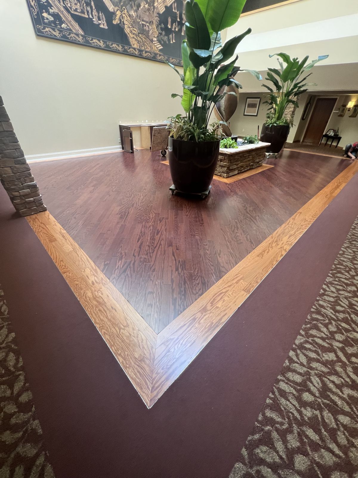 Dark stained hardwood with a light oak border in a commercial lobby with large planters