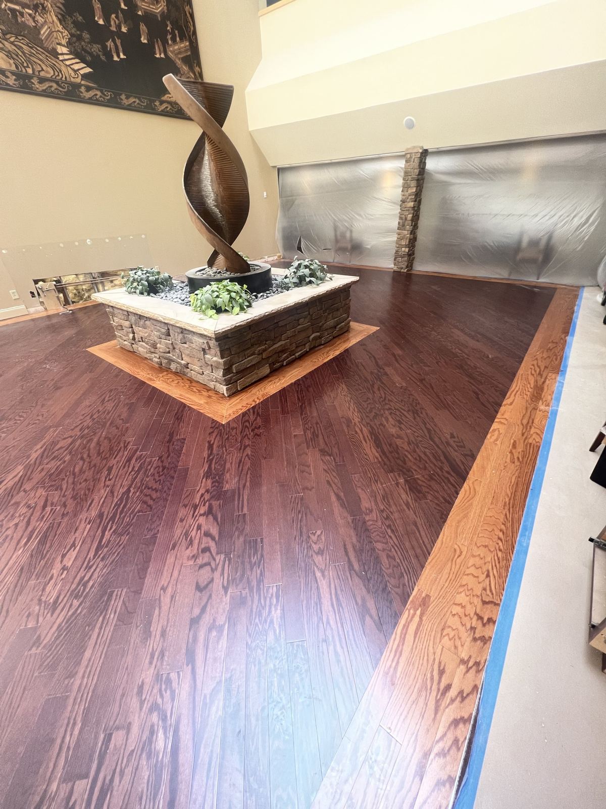 Dark stained hardwood with a light border around a stone fountain in a commercial lobby