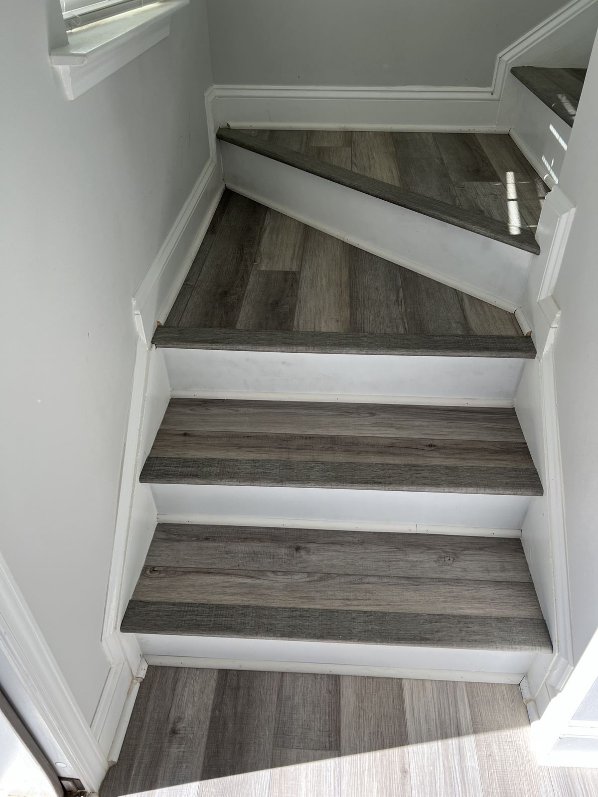 Gray wood-look stair treads on a winding staircase with white risers